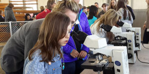A young girl looking into a microscope.